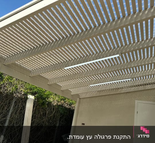 פרגולה מעץ עם קורות לבנות בגינה